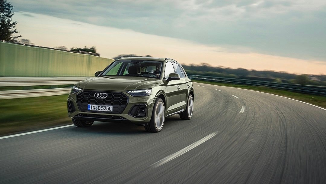 Un audi Q5 qui prend une courbe sur la route.