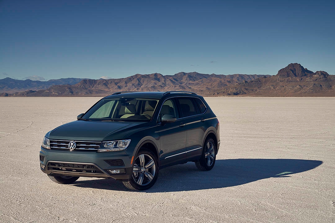 Un Volkswagen Tiguan 2021 stationné sur le sable avec des montagne en arrière plan. 