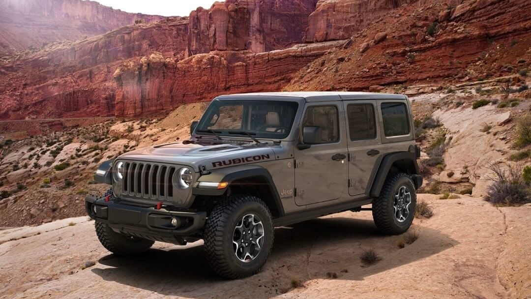 Un Jeep wrangler stationné en haut d'une petite colline rocheuse.