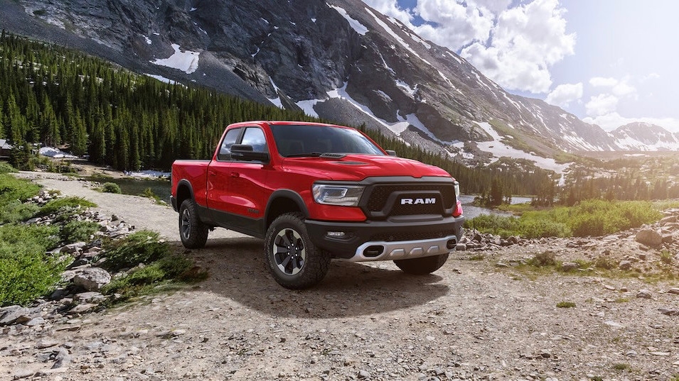 Le RAM 1500 stationné sur un chemin de gravel avec un paysage de montagne au levé du soleil.